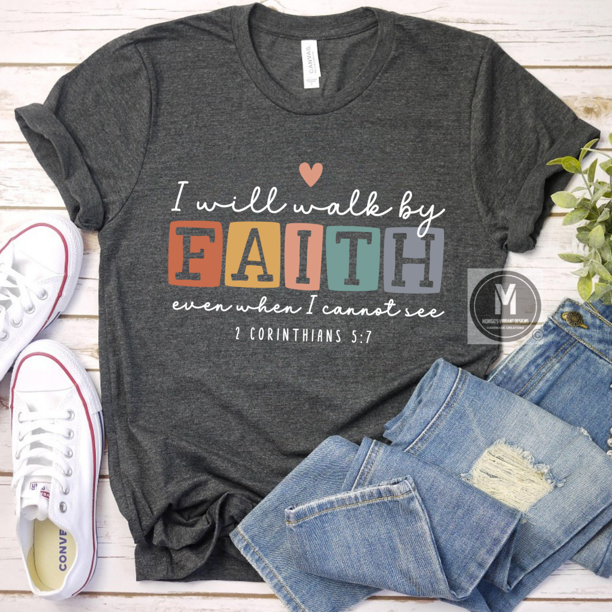 Gray t-shirt with motivational quote, jeans, and sneakers on a wooden surface