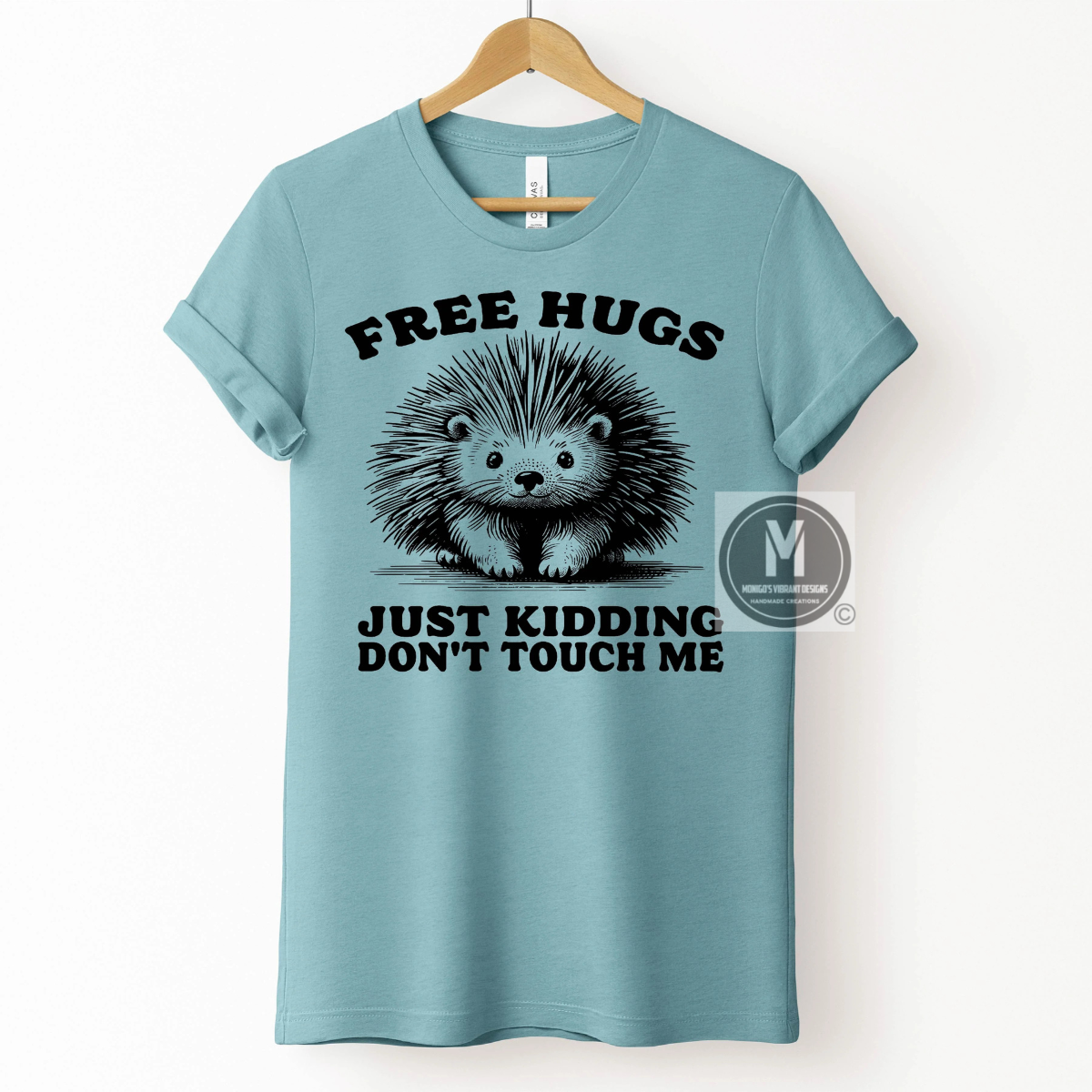 A blue t-shirt featuring a cute hedgehog graphic and the text "FREE HUGS JUST KIDDING DON'T TOUCH ME."