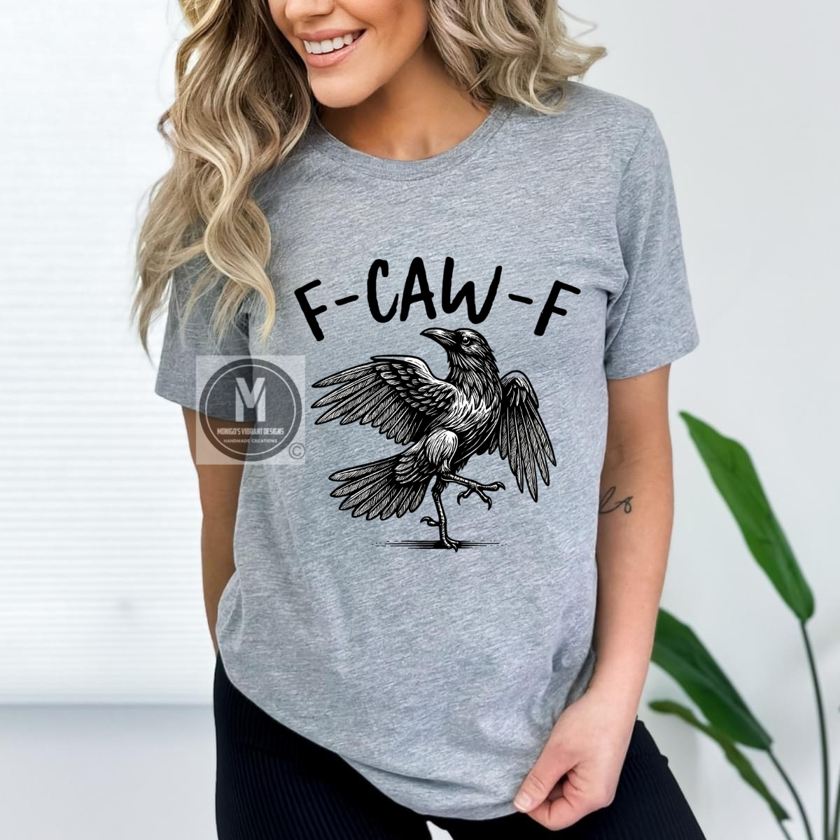“Heather gray unisex t-shirt with a humorous crow design and the words ‘F-CAW-F,’ styled casually indoors.”