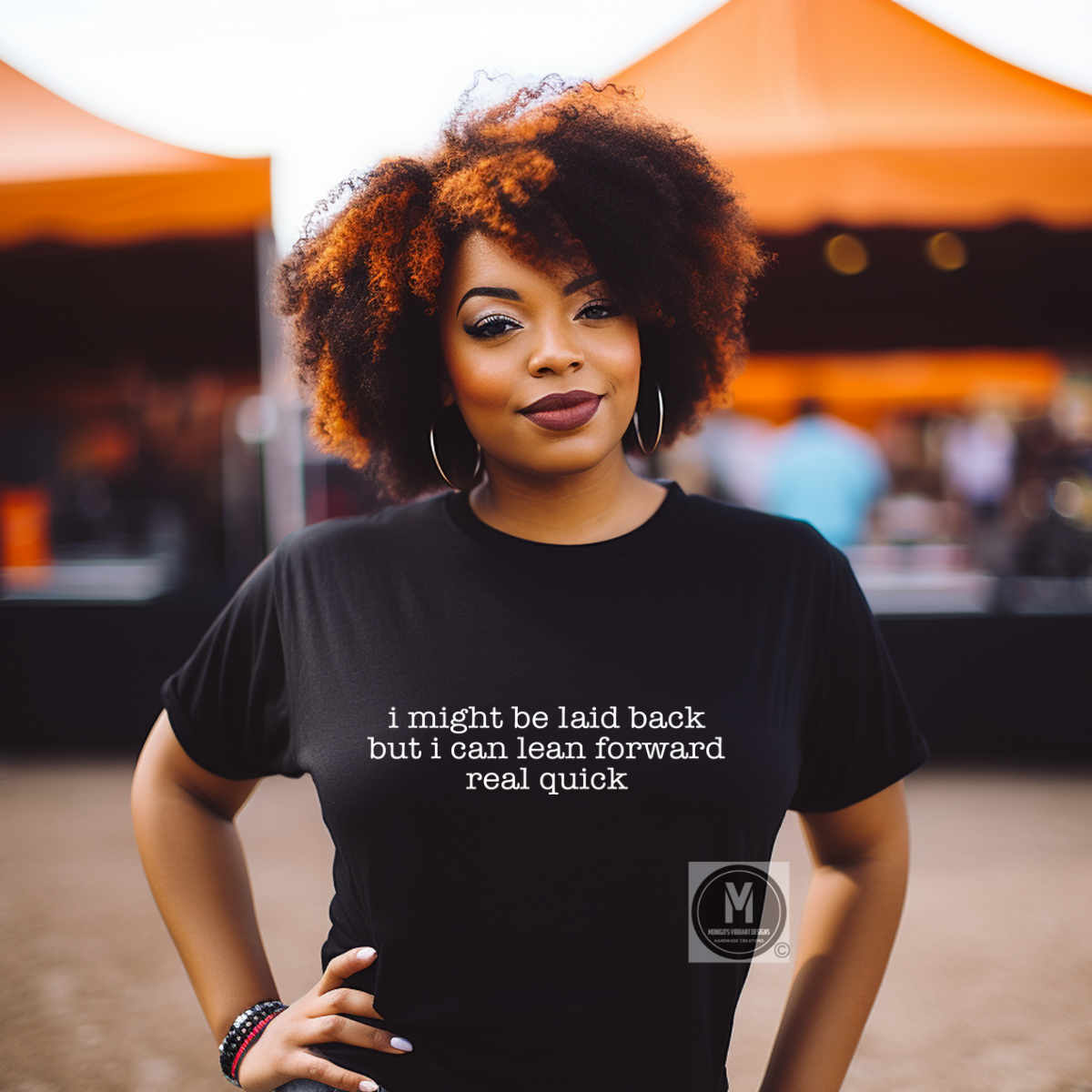 Woman wearing a black t-shirt with text, standing in front of orange tents.