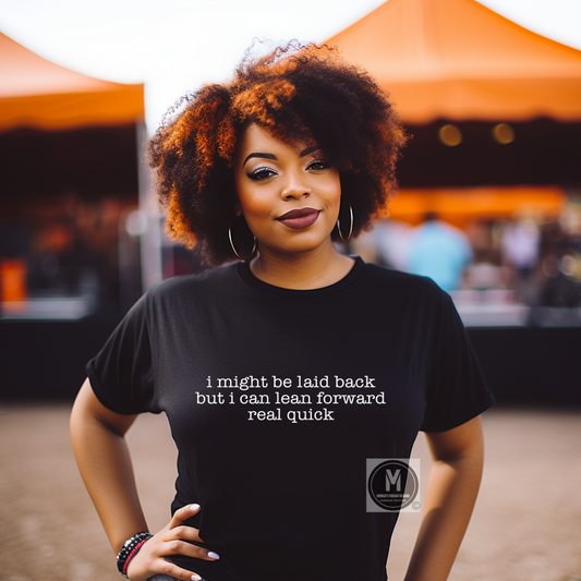 Woman wearing a black t-shirt with text, standing in front of orange tents.