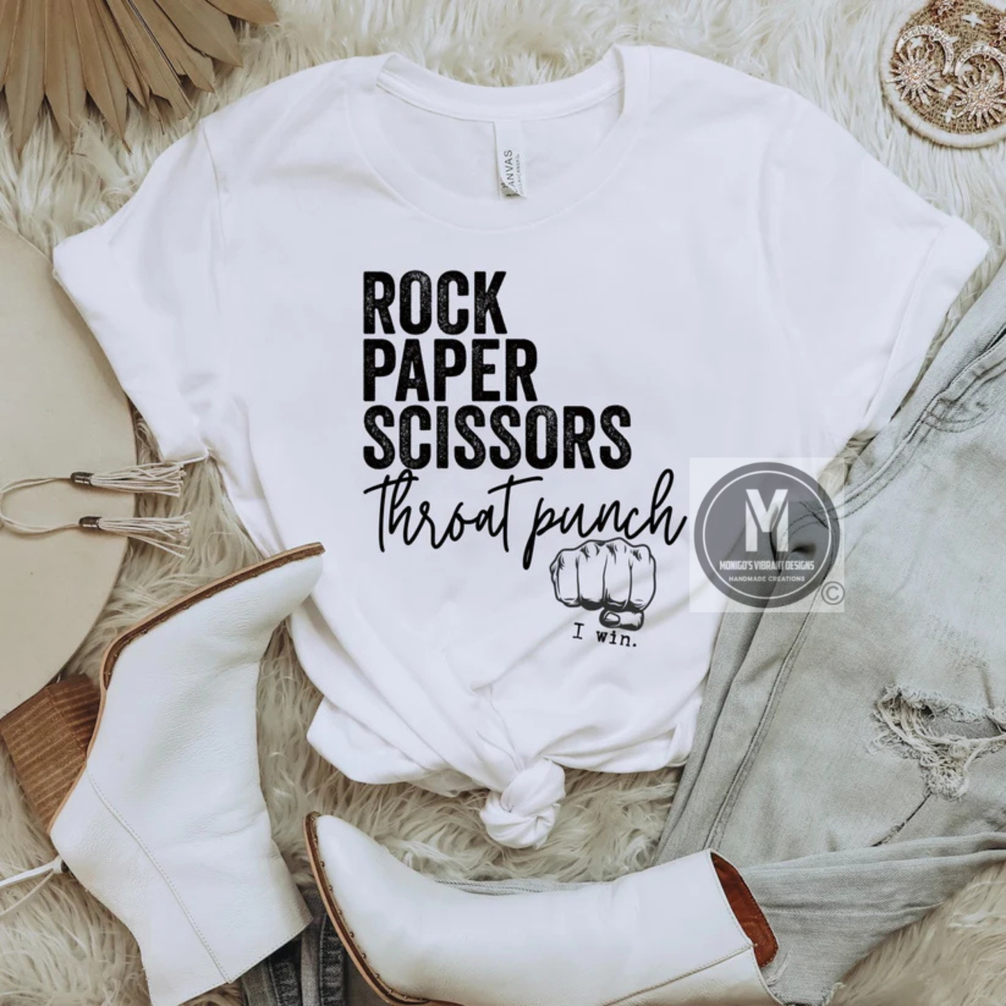 White t-shirt with 'Rock Paper Scissors Throat Punch I win' text on a textured surface with accessories.