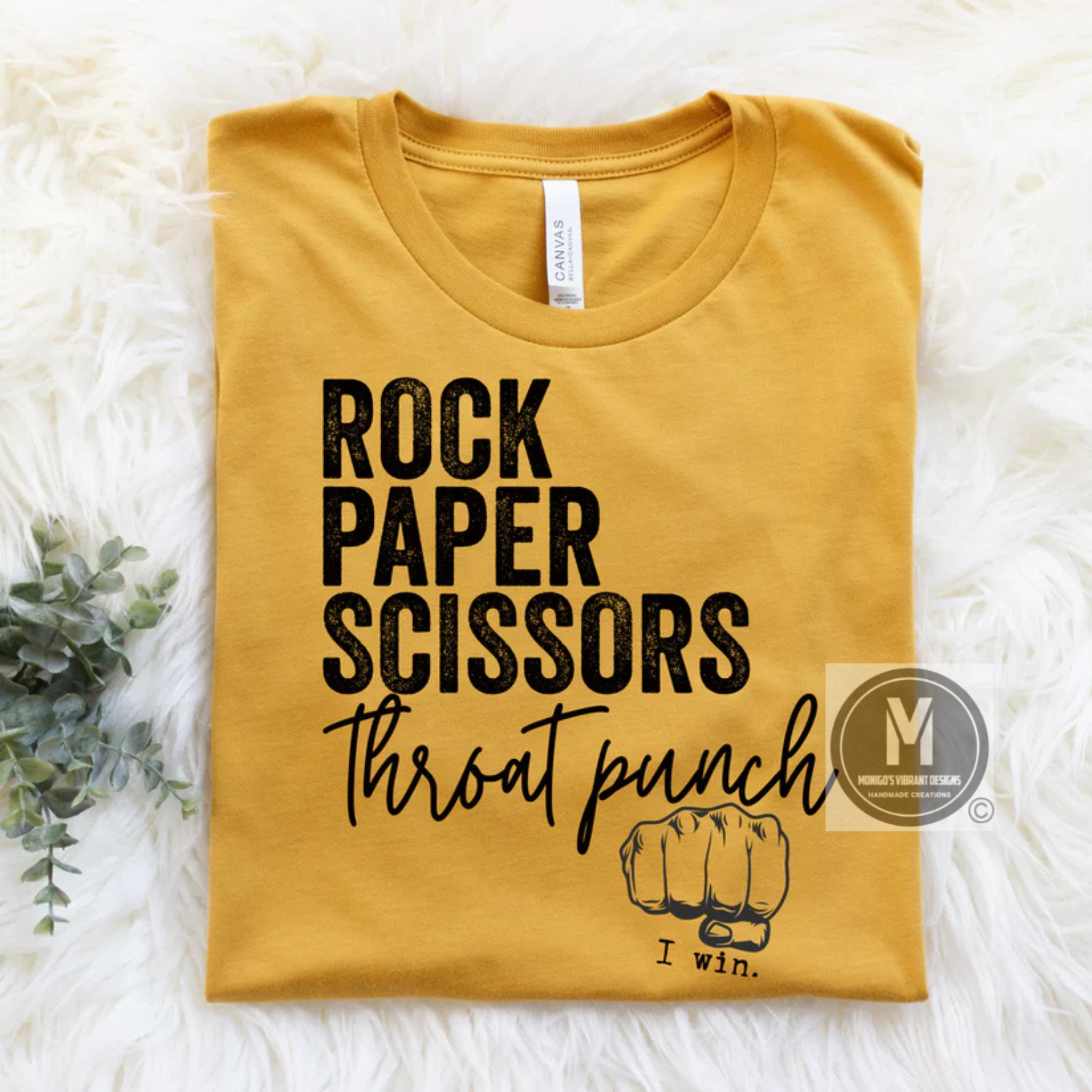 Yellow t-shirt with 'Rock Paper Scissors Throat Punch I Win' text on a white surface